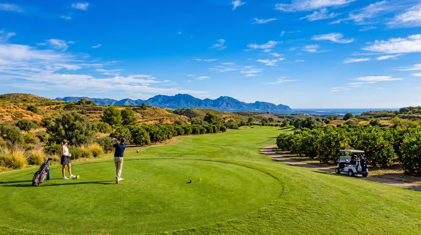 A sun-drenched golf fairway at Mediterráneo Golf in Borriol, Castellón, with lush green turf contrasting against the warm ochre of the surrounding Mediterranean landscape, orange trees lining the edge